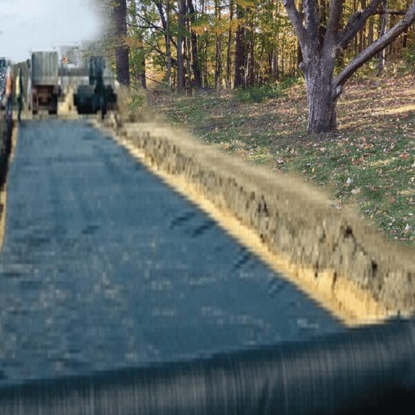 A truck driving down the road next to trees.