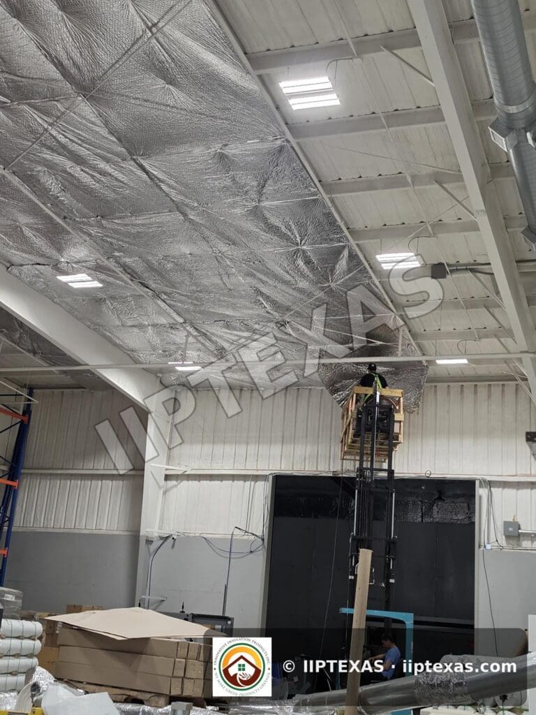 IIP Texas crew installing reflective bubble foil insulation under the roof of a metal building