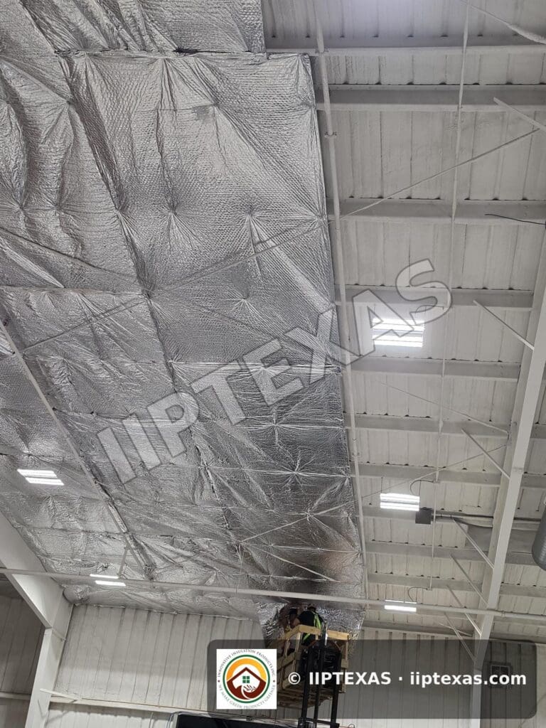 IIP Texas crew installing reflective bubble foil insulation under the roof of a metal building