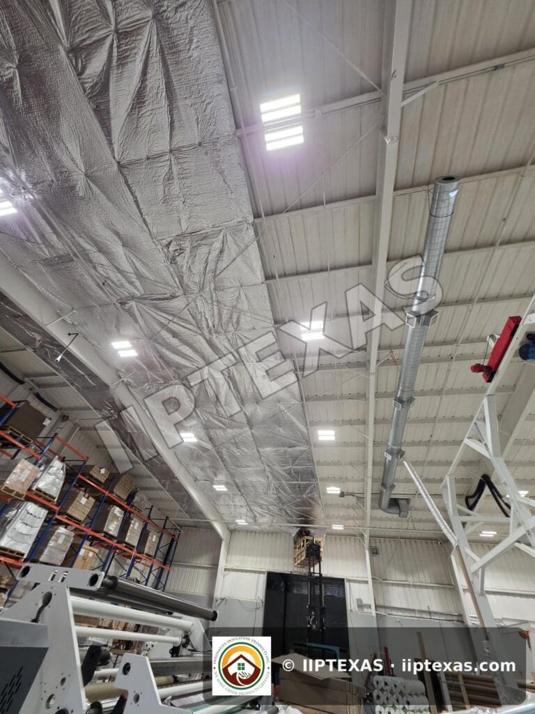 IIP Texas crew installing reflective bubble foil insulation under the roof of a metal building