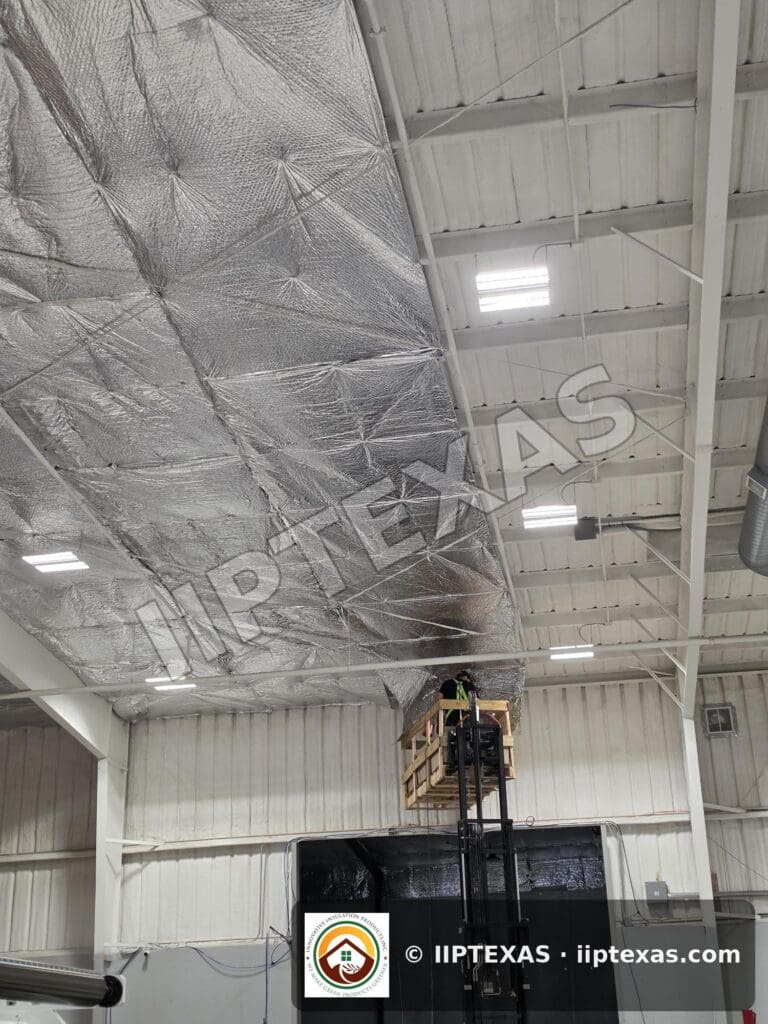 IIP Texas crew installing reflective bubble foil insulation under the roof of a metal building